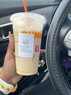 a person holding a drink in their hand while sitting in the driver's seat