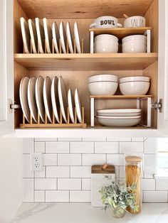 a kitchen cabinet filled with dishes and plates