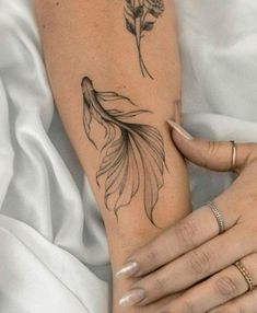 a woman's arm with a tattoo on it and a goldfish in the middle