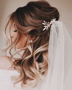 a woman with long hair wearing a veil and flowers in her hair is seen from the side