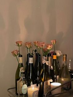 several bottles of wine and candles are arranged on a shelf in front of a wall