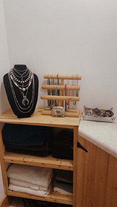 a wooden cabinet with necklaces and other items on it's shelf next to a white wall