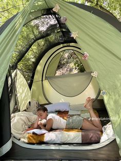 a woman laying in a tent reading a book