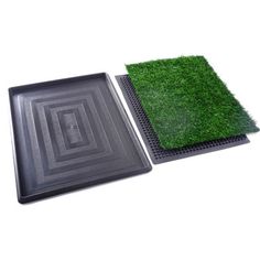 two black trays with grass on them, one is empty and the other has a square