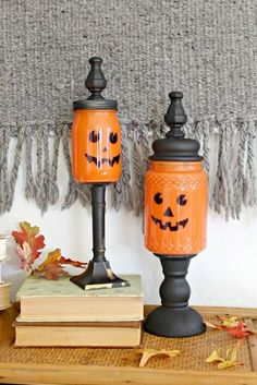 two pumpkin jars sitting on top of a wooden table next to books and a scarf