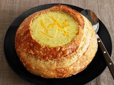 a black plate topped with soup and bread