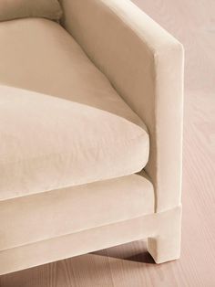 a white couch sitting on top of a hard wood floor next to a pink wall