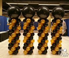 black and gold balloons are arranged in the shape of three spirals on top of each other