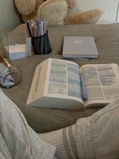 a teddy bear sitting on top of a bed next to an open book