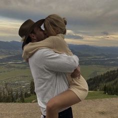 a man and woman embracing each other on top of a mountain