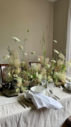 the table is set with white flowers and silverware