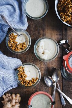 three bowls filled with food sitting on top of a wooden table next to spoons