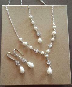 three necklaces with pearls and crystal beads on a piece of brown paper next to a pair of earrings