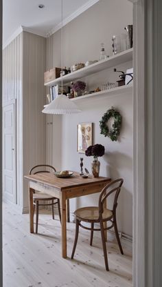 a dining room table with two chairs and shelves