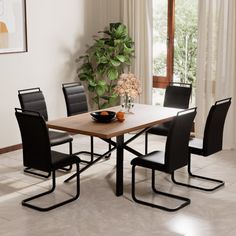 a dining room table with four chairs and a bowl of fruit on the table next to it