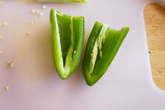 two pieces of green vegetable sitting on top of a cutting board