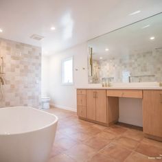 a bath room with a tub a sink and a mirror on the wall in it