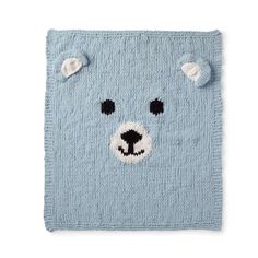 a blue knitted bear rug with black eyes and nose on it's face