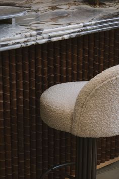 a white bar stool sitting next to a counter with a marble top and metal barstool