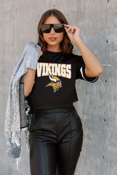 a woman wearing black leather pants and a t - shirt with the word vikings on it