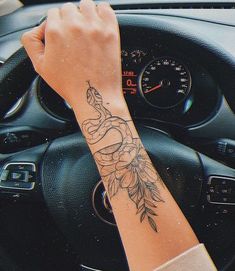 a woman's arm with a flower tattoo on it, sitting in a car