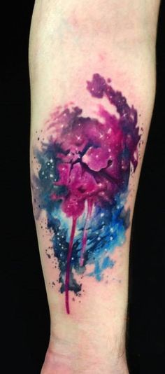 a colorful tattoo on the leg of a person with watercolor paint splatters