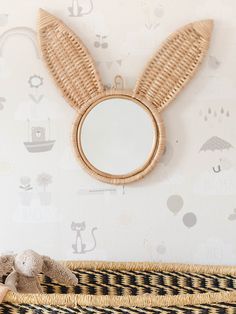 a stuffed animal sitting on top of a bed next to a wall mounted round mirror