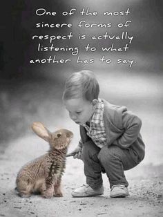 a little boy kneeling down next to a bunny and touching it's face with his hand