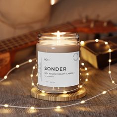 a candle sitting on top of a table next to a string of lights and a guitar