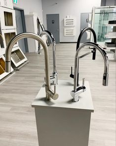 two stainless steel kitchen faucets sitting on top of a counter in a store