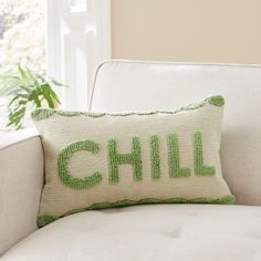 a white couch with a green pillow that says chill on it