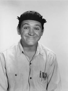 black and white photograph of a man with a hat on top of his head smiling at the camera