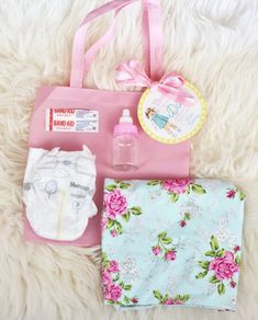 baby items laid out on top of a white furnishing floor next to a pink bag