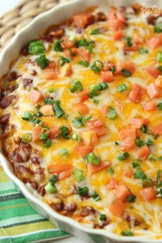 a casserole dish filled with beans, cheese and veggie toppings