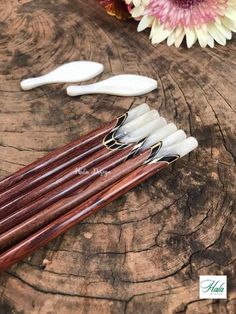 five wooden chopsticks with white handles on top of a wood table next to flowers