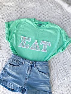 These classic and vintage-style letters are perfect for new and seasoned sorority women alike! Features double-stitched cottage-style flower letters on a white background attached to a comfortable unisex mint tee. This seller is licensed with Affinity Licensing to ensure a verified, quality product. Care Instructions: Machine wash cold, inside out; Tumble dry low; Low iron as needed Casual Summer T-shirt With Letter Embroidery, Casual T-shirt With Letter Embroidery For Spring, Spring Sorority Cotton T-shirt, Sorority Cotton T-shirt For Spring, Sorority Style Cotton T-shirt For Spring, White Letter Embroidery T-shirt For Spring, White T-shirt With Letter Embroidery For Spring, Cute Letter Embroidery T-shirt For Spring, White Embroidered T-shirt For Spring