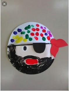 a paper plate that has a man's face painted on it with different colors