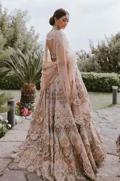 a woman in a wedding dress standing on a stone walkway with her back to the camera