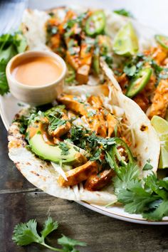 chicken and avocado tacos on a plate with salsa, cilantro, and lime wedges