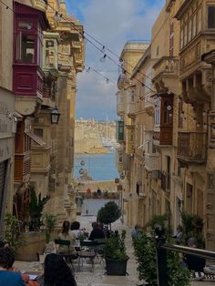 an alley way with people sitting at tables and looking out over the water on a cloudy day