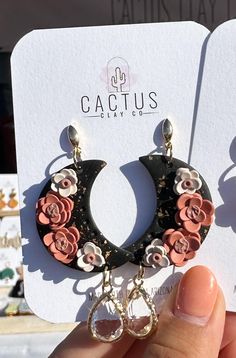 a pair of earrings with flowers hanging from it's earring hooks in front of a card