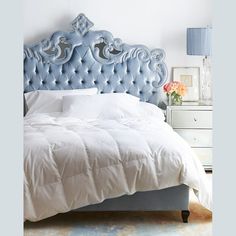 a bedroom with a blue headboard and white comforter on top of the bed