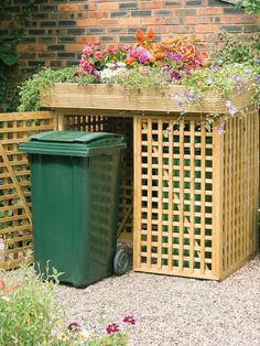 a green trash can sitting next to a wooden planter