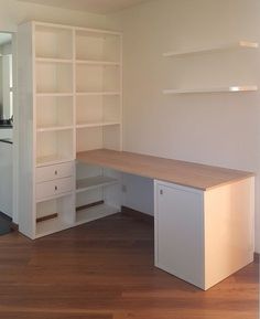 an empty room with white bookcases and wooden floors