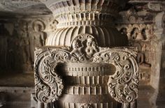 an intricately carved sculpture in the middle of a room with stone walls and pillars