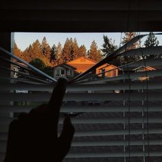 someone is looking out the window with their hand in front of them and some houses