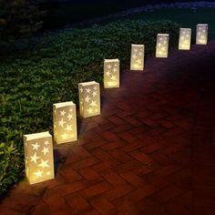 lighted paper bags lined up in the shape of stars on a brick path at night