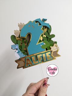 a person holding up a paper cutout with the number two in it's center