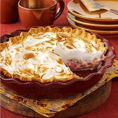 a pie sitting on top of a wooden table next to plates and utensils