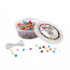 a container filled with lots of different colored beads next to a string of white cord